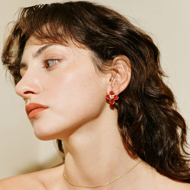 Woman wearing red floral statement earrings and a delicate gold necklace