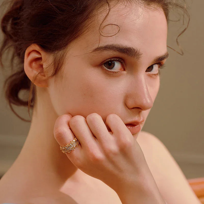 Woman wearing a gold-plated statement ring with sparkling crystals, close-up portrait
