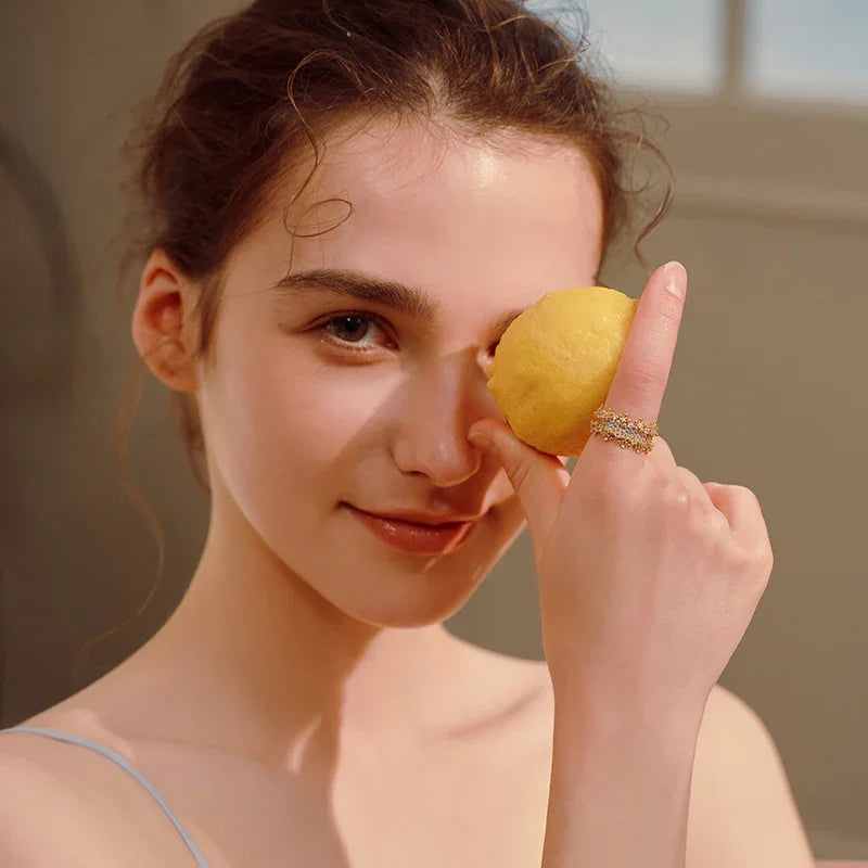 Woman with gold-plated crystal ring holding a lemon, elegant jewelry close-up