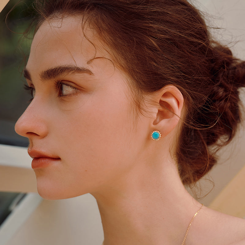 Woman wearing gold-plated turquoise stud earrings, elegant jewelry close-up