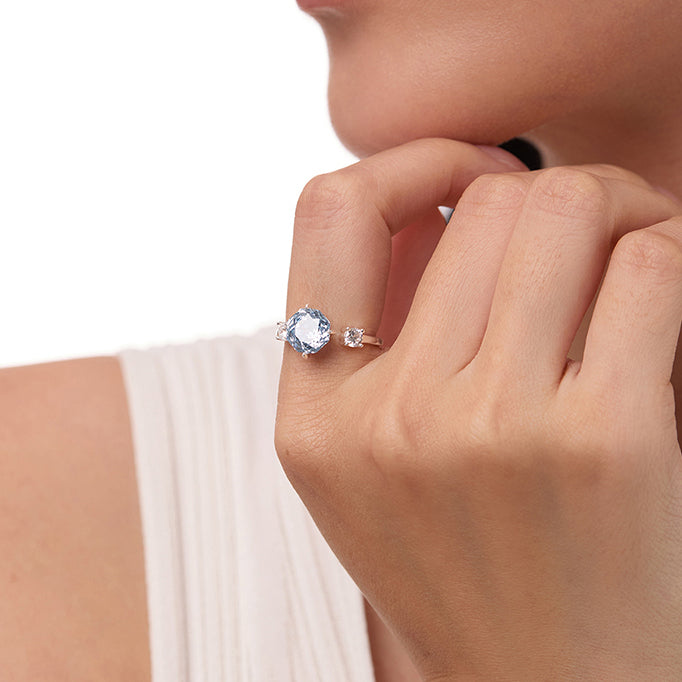 Gold-plated ring with large blue gemstone and small clear stone on woman's hand
