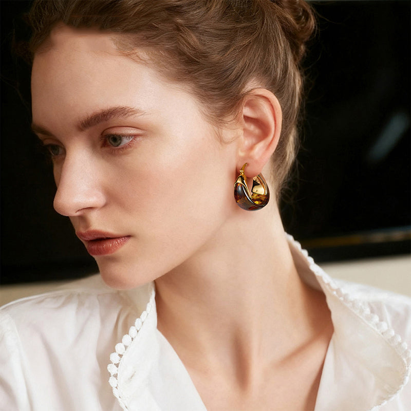 Woman wearing gold-plated statement hoop earring with tortoiseshell detail